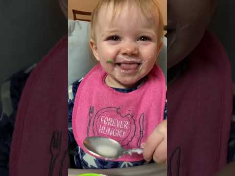 Curious baby drinks milk with a spoon